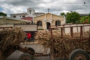 A truck carrying sugar cane passes a woman and child outside a church in the Dominican Republic in May 2021. Foto: Washington Post photo by Salwan Georges