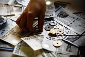     H¬nd samler mØnt op blandt danske kontanter, mØnter, pengesedler, penge.  Foto: Lærke Posselt