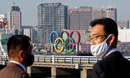FILE PHOTO: Men wearing face masks watch as giant Olympic rings, which were temporarily taken down in August for maintenance amid the coronavirus disease (COVID-19) outbreak, are transported for reinstallation at the waterfront area at Odaiba Marine Park in Tokyo, Japan December 1, 2020. REUTERS/Kim Kyung-Hoon/File Photo