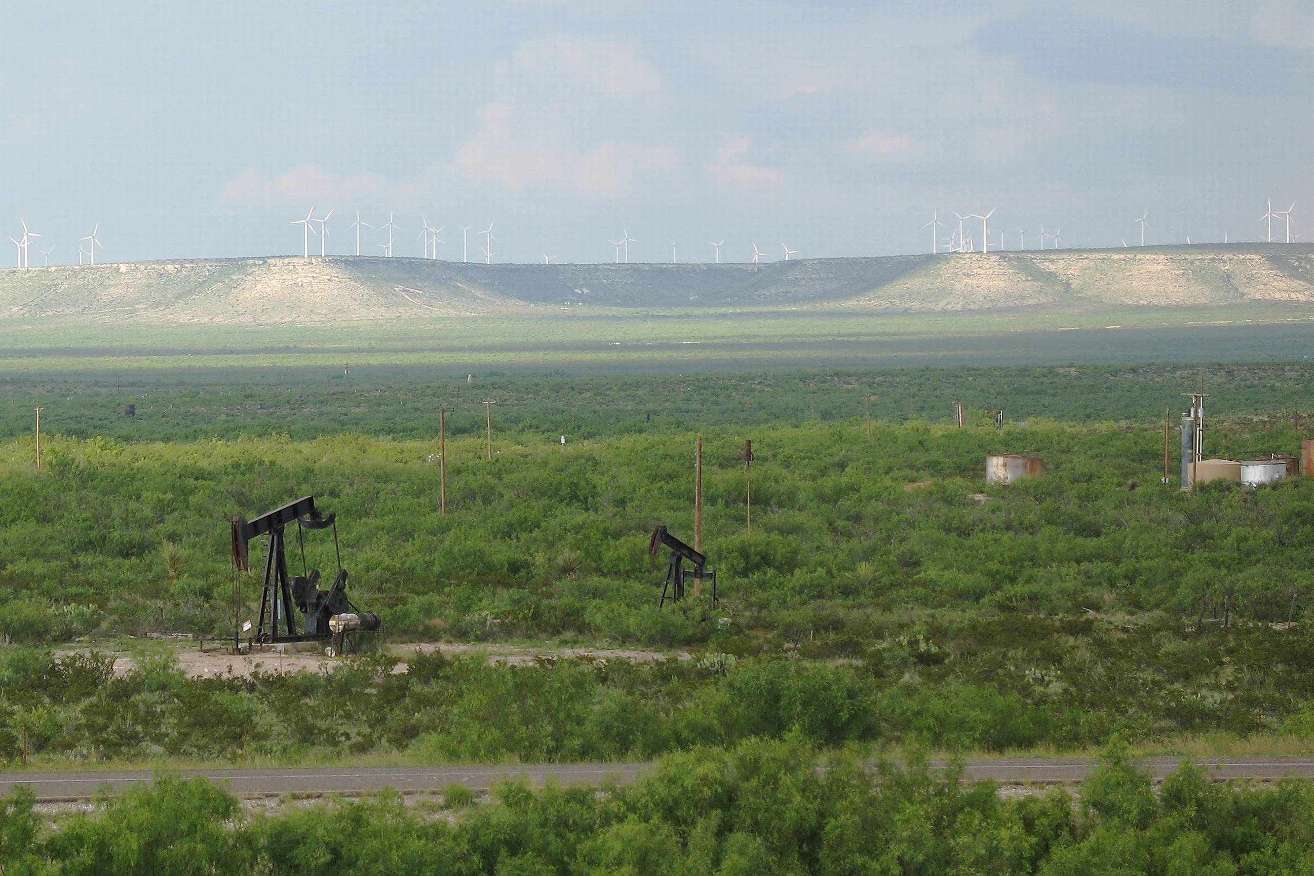 Nyt og gammelt mødes. I forgrunden stripperoliebrønde og de tilhørende lagertanke. I baggrunden på højdedraget vindmøller. 