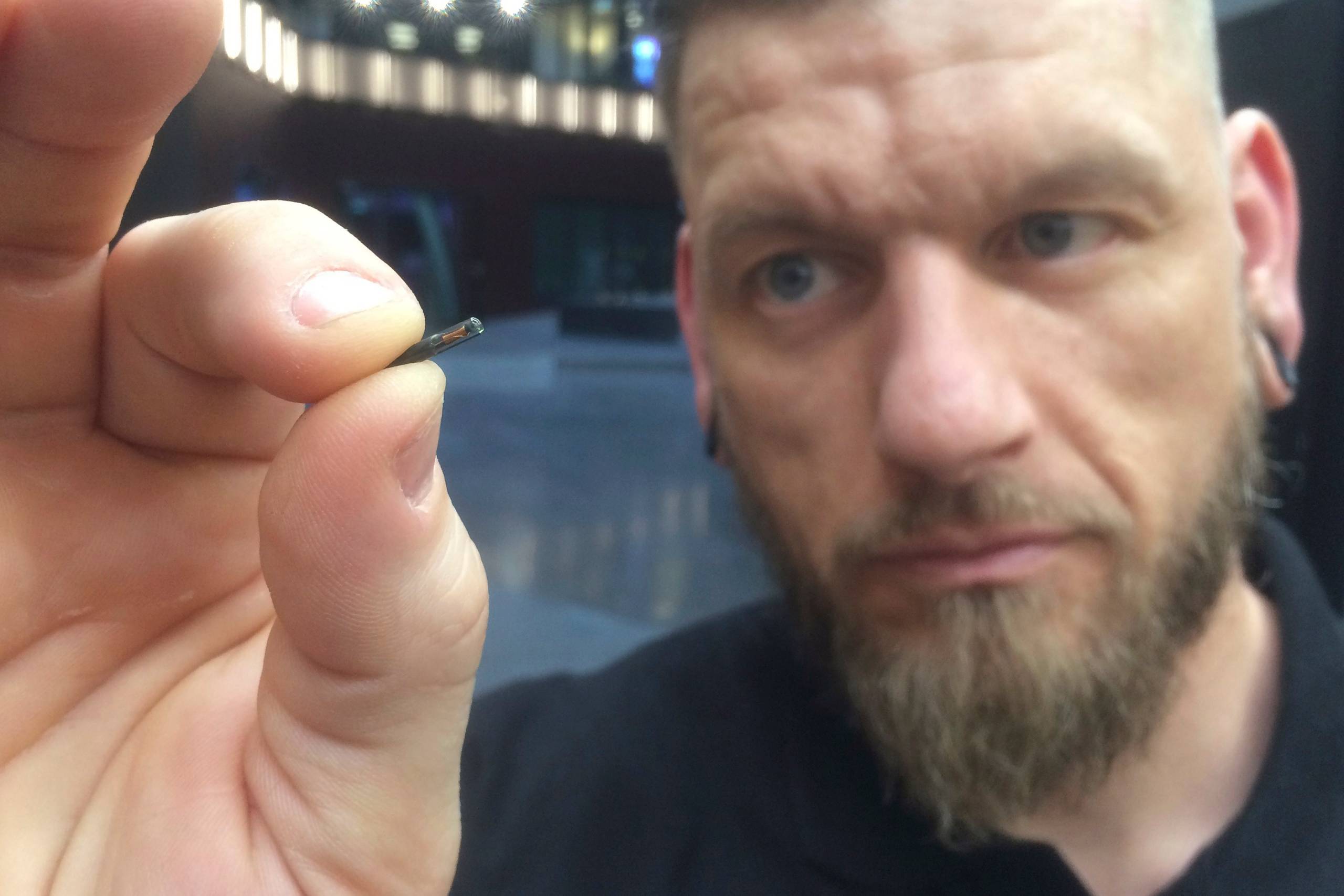 Self-described “body hacker” Jowan Osterlund from Biohax Sweden, holds a small microchip implant, similar to those implanted into workers at the Epicenter digital innovation business centre during a party at the co-working space in central Stockholm, Tuesday March 14, 2017. Microchips are being implanted into volunteers to help them open doors and operate office equipment, and its become so popular that members of the Epicentre cyborg club hold regular parties for those with the tiny chips embedded in their hands. (AP Photo/James Brooks)