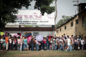 People stand in front of a Socialist Party office while waiting in line to buy groceries at a supermarket in Charallave, Venezuela, on April 25, 2016. Photo: Wilfredo Riera/Bloomberg